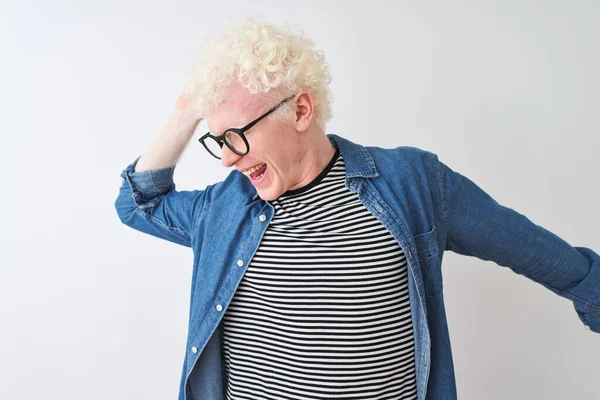 Young albino blond man wearing denim shirt and glasses over isolated white background Dancing happy and cheerful, smiling moving casual and confident listening to music