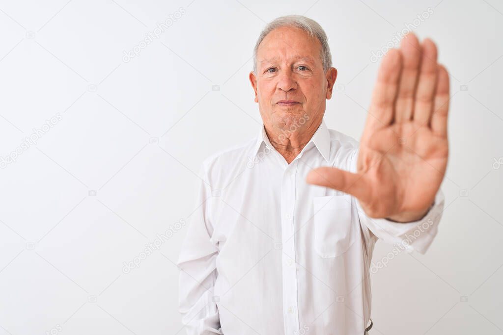 Senior grey-haired man wearing elegant shirt standing over isolated white background doing stop sing with palm of the hand. Warning expression with negative and serious gesture on the face.