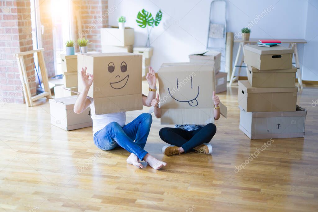 Couple wearing funny cardboard boxes with happy faces