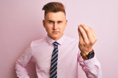 Genç yakışıklı işadamı gömlek ve kravat izole pembe arka plan üzerinde duran giyen el ve parmakemin ifade ile İtalyan jest yapıyor