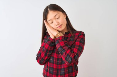 İzole edilmiş beyaz arka planda dikilen, rahat ceketli genç Çinli kadın yorgun düşler kuruyor ve elleri ile birlikte poz verirken kapalı gözlerle gülümsüyor..