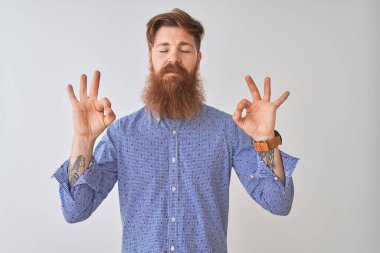 Genç kızıl İrlandalı adam izole beyaz arka plan üzerinde duran rahat gömlek giyen rahat rahat ve gözleri parmakları ile meditasyon jest yapıyor kapalı gülümseyerek. Yoga konsepti.