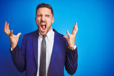 Genç yakışıklı iş adamı mavi arka planda çılgın ve başarıyı kutluyor kollarını kaldırmış ve gözlerini kapatmış heyecanla haykırıyor. Kazanan konsept