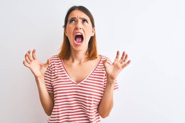 Güzel kızıl saçlı kadın, izole edilmiş arka planda sıradan kırmızı tişörtler giyiyor. Deli gibi bağırıyor, agresif bir ifade ve kollarla bağırıyor. Hayal kırıklığı konsepti.