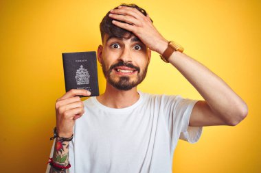 Kanada pasaportu takan genç bir adam izole edilmiş sarı arka planda el ele, utanç ve şaşkınlık dolu, sinirli ve hayal kırıklığına uğramış bir halde. Hata için korku ve üzüntü.