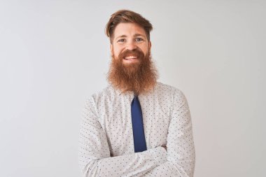 Genç kızıl saçlı İrlandalı işadamı, izole edilmiş beyaz arka planda durup kollarını kavuşturup kameraya bakarken gülümsüyor. Pozitif kişi.