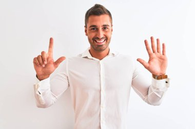 Soyutlanmış arka planda zarif gömlekler giyen genç yakışıklı iş adamı yedinci parmaklarını gösterip işaret ederken kendine güvenen ve mutlu bir şekilde gülümsüyor..