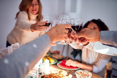 Aile ve arkadaşlar geleneksel yemek ve dekorasyonla Noel arifesini evde kutluyor, bir kadeh şarapla en iyi dileklerimizi sunuyorlar.