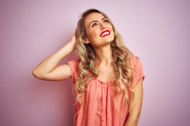 Young beautiful woman wearing t-shirt standing over pink isolated background smiling confident touching hair with hand up gesture, posing attractive and fashionable