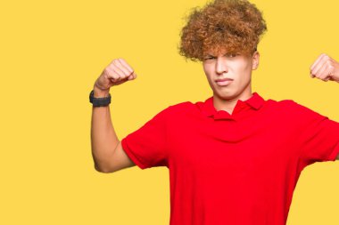 Kırmızı t-shirt gösteren kol kasları gururlu gülümseyen giyen afro saçlı genç yakışıklı adam. Fitness kavramı.