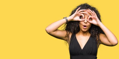 Kıvırcık saçlı genç güzel kız moda etek giyen dürbün dil dışarı yapışması gibi ok jest yapıyor, gözleri parmaklardan bakıyor. Çılgın ifade.