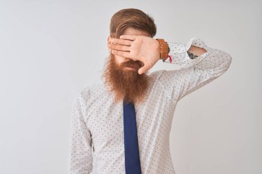 Genç kızıl saçlı İrlandalı işadamı, izole edilmiş beyaz arka planda duruyor. Gözleri elle örtüyor, ciddi ve üzgün görünüyor. Görme, saklama ve reddetme konsepti