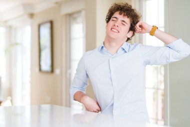 Kıvırcık saçlı genç iş adamı başını geriye doğru uzatıyor, yorgun ve rahat, uykulu ve sabahın erken saatleri için esniyor.