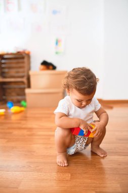 Anaokulunda bir sürü oyuncağın etrafına taş döşeyen sevimli bir çocuk.