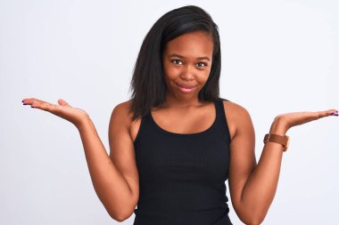 Güzel genç Afro-Amerikan kadın izole arka plan clueless ve şaşkın bir ifadeyle kollar ve eller kaldırdı. Şüphe kavramı.