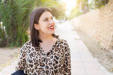 Bahçede mutlu gülümseyen kırmızı dudaklı genç güzel kadın