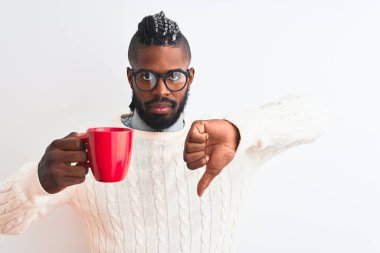 Örgülü Afro-Amerikalı bir adam izole edilmiş beyaz arka planda kahve içiyor. Kızgın bir yüzü var. Eksi işareti baş parmakları aşağıda, reddedilme konsepti reddedildi.