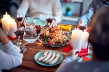 Aile ve arkadaşlar Noel arifesini geleneksel yemek ve dekorasyonla birlikte evde yemek yiyorlar. Hep birlikte masaya oturuyorlar.