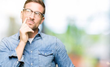 Yakışıklı adam çene üzerinde el ile gözlük giyiyor soru hakkında düşünme, dalgın ifade. Düşünceli bir yüz ile gülümsüyor. Şüphe kavramı.