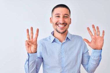 Genç yakışıklı iş adamı izole edilmiş arka planda duruyor. Sekiz numaralı parmaklarıyla işaret ediyor ve gülümsüyor. Kendinden emin ve mutlu..