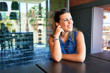 Restoranda oturan genç ve güzel bir kadın yaz tatilinin tadını çıkarıyor.