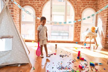 Güzel Afrikalı Amerikalı çocuk anaokulunda tenis raketiyle oynuyor.