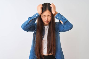 Kotlu gömlek giyen genç Çinli bir kadın izole edilmiş beyaz arka planda duruyor. Ağrı ve migren yüzünden baş ağrısı ve stresten muzdarip. Ellerini başının üstüne koy..