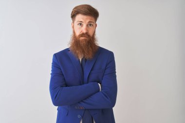 İzole edilmiş beyaz arka planda duran takım elbiseli genç kızıl saçlı işadamı yüzünde ciddi bir ifadeyle rahatlamış. Basit ve doğal bir şekilde kameraya bakıyorsun..