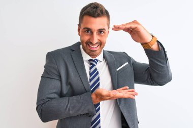 Takım elbiseli ve kravatlı genç yakışıklı iş adamı, izole edilmiş arka plan hareketleriyle büyük ve büyük boyut işareti, ölçü sembolü gösteriyor. Kameraya bakıp gülümsüyor. Ölçüm konsepti.