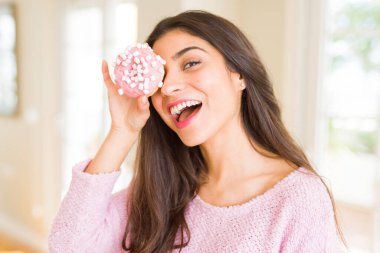 Göz üzerinde pembe çörek bakarak gülümseyen güzel genç kadın