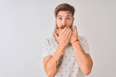 İzole edilmiş beyaz arka planda duran kırmızı saçlı, polo giyen genç bir adam yanlışlıkla ağzı ellerle kapatarak şok geçirdi. Gizli konsept.