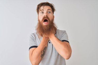 Gri polo giyen genç kızıl saçlı adam izole edilmiş beyaz arka planda durup bağırıyor ve boğuluyor çünkü acı verici bir boğulma. Sağlık problemi. Boğulma ve intihar konsepti.