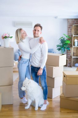 Karton kutular etrafında yeni evde duran köpek ile genç güzel çift