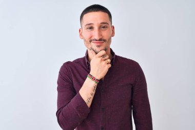 Genç ve yakışıklı bir iş adamı izole edilmiş arka planda durup kameraya kollarını kavuşturup gülümseyerek ve çenesini kaldırarak bakıyor. Olumlu düşünüyorum..