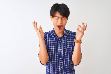 İzole edilmiş beyaz arka plan üzerinde dikilmiş, kollarını kaldırmış ve gözleri kapalı heyecanlı bir şekilde çılgın ve çılgın bir başarıyı kutlayan sıradan mavi tişörtlü genç Çinli bir adam. Kazanan konsept