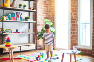 Anaokulunda bir sürü oyuncakla bekleyen güzel bir çocuk.