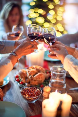 Aile ve arkadaşlar Noel arifesini geleneksel yemek ve dekorasyonla birlikte evde yemek yiyorlar. Hep birlikte masaya oturuyorlar.