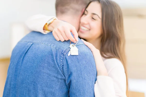 Bonito jovem casal abraçando no amor e mostrando as chaves do novo h — Fotografia de Stock