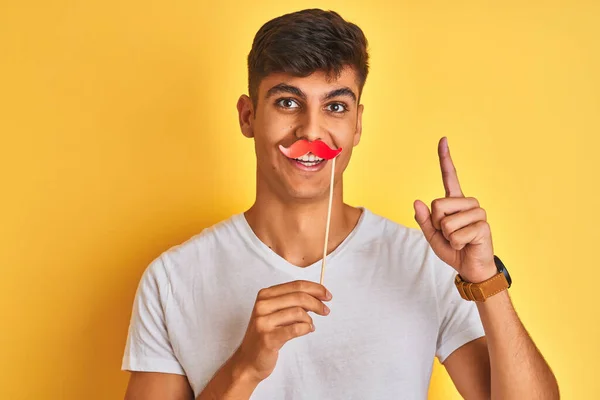 Jovem Indiano Segurando Bigode Fanny Sobre Fundo Amarelo Isolado Surpreso — Fotografia de Stock