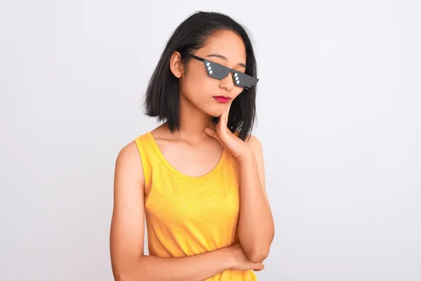 Young beautiful chinese woman wearing thug life sunglasses over isolated white background thinking looking tired and bored with depression problems with crossed arms.