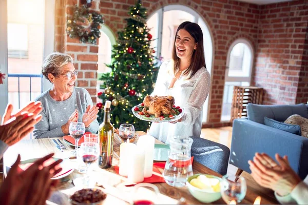 Family and friends dining at home celebrating christmas eve with traditional food and decoration, showing proud turkey cooking