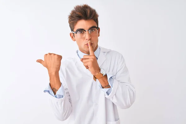 若いハンサムな科学者の男性は 孤立した白い背景の上に眼鏡やコートを着用し 唇の側に手を指して上の指で静かにするように求めている 沈黙と秘密の概念 — ストック写真