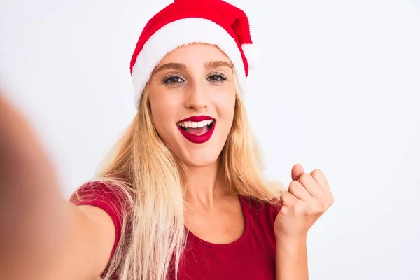 戴着圣诞圣诞圣诞礼帽的女人在孤独的白色背景下 在镜头前自拍 自豪地尖叫着庆祝胜利和成功 激动地欢呼着自己的感情 — 图库照片