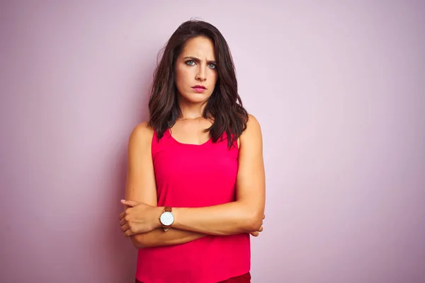 Young beautiful woman wearing t-shirt standing over pink isolated background skeptic and nervous, disapproving expression on face with crossed arms. Negative person.