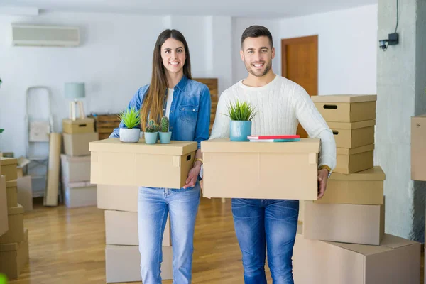 Giovane coppia si trasferisce in una nuova casa, sorridente felice holding cardboa — Foto Stock