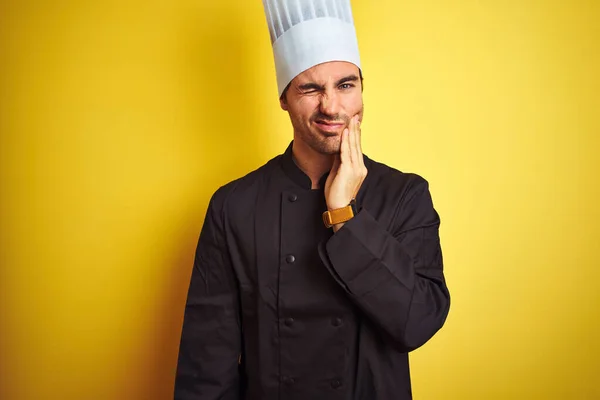 年轻厨师 身穿制服 头戴帽子 站在孤立的黄色背景上 手牵着手 因牙痛或牙病而痛苦不堪 牙科医生的概念 — 图库照片