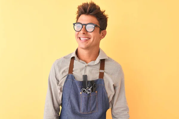 Junger Gutaussehender Friseurmeister Mit Schürze Und Brille Vor Isoliertem Gelben — Stockfoto