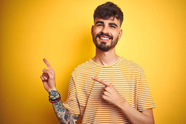Mladý Muž Tetováním Pruhovaným Tričkem Který Stojí Nad Izolovaným Žlutým — Stock fotografie
