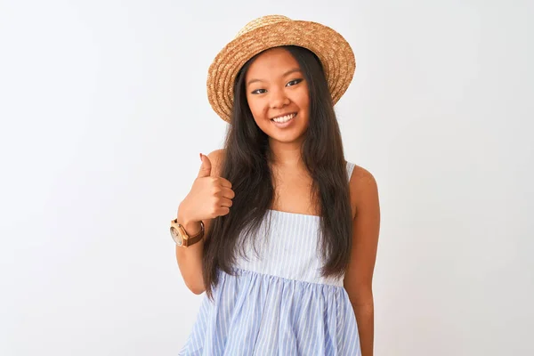 年轻的中国女人穿着条纹衣服 头戴帽子 站在孤独的白色背景上 手举着快乐的大拇指 用成功的表情看着摄像机 — 图库照片