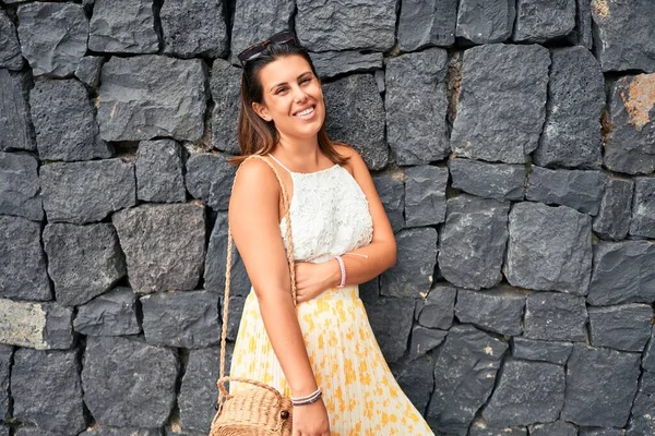 Beautiful girl leaning on the wall, young friendly woman smiling happy on a sunny day of summer